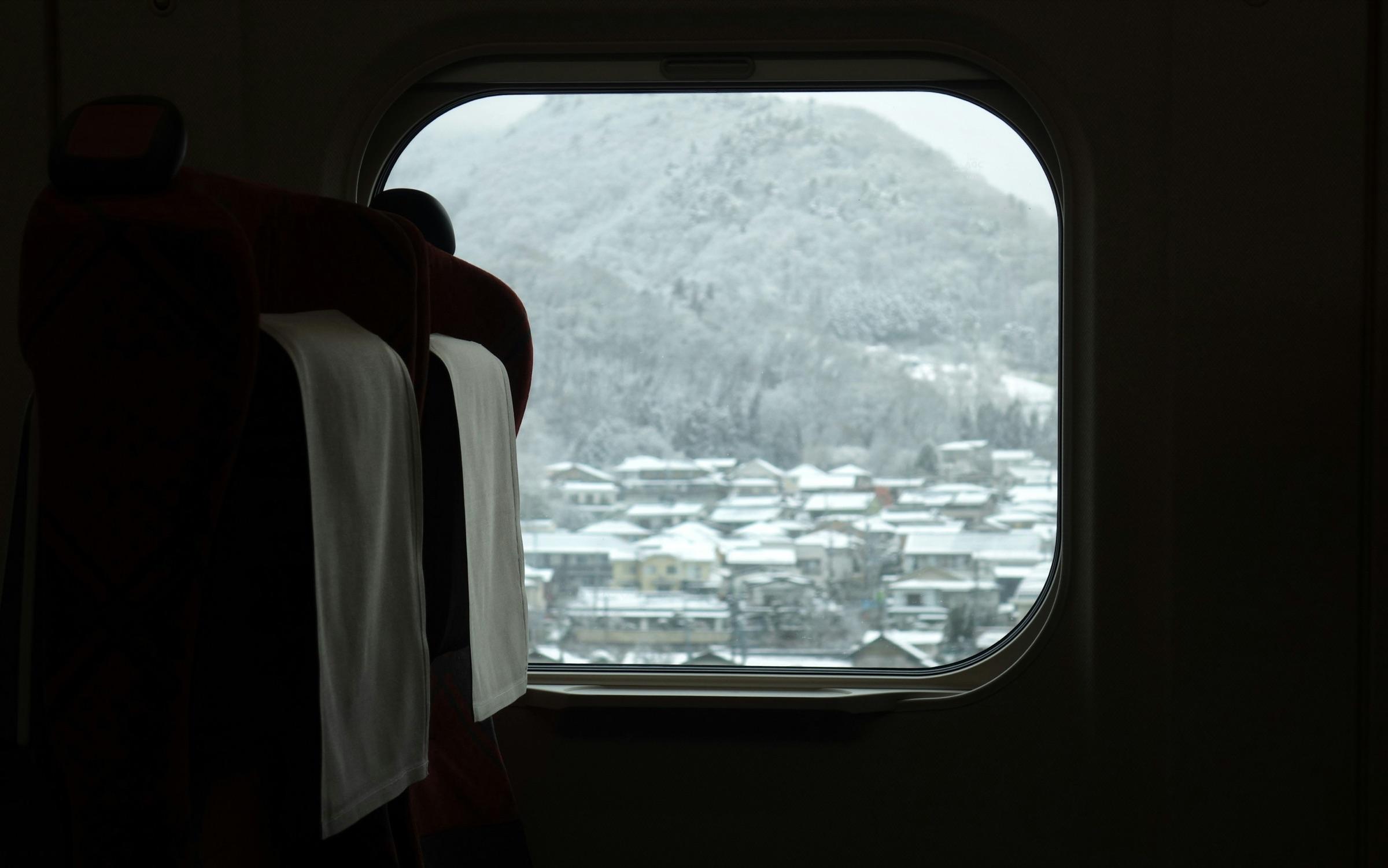 列車の窓から眺める、雪の町と山